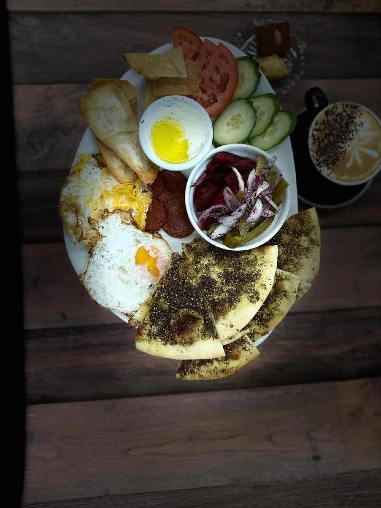 A Habibi breakfast platter with eggs, zaatar, labneh, olives and fresh vegetables